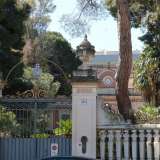 La residenza e il suo ampio giardino sono racchiusi da una lunga balaustra bianca e un raffinato cancello in parte dorato: quest'ultimo � incastrato tra due colonne sormontate da sculture consistenti in vasi di pietra colmi di pigne